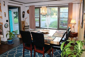 Un comedor con una amplia mesa de madera, sillas negras y una lámpara colgante decorativa.