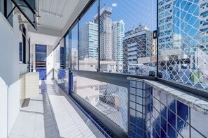 Un couloir donnant sur une vue panoramique de la ville grâce à un mur de verre.