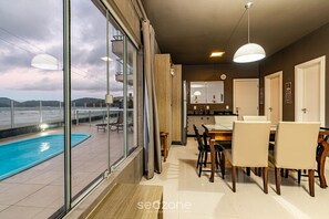 Eine moderne Küche mit Essbereich, einem Pool und Meerblick.