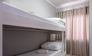 A bunk bed room with a headboard, a bedside table, and a window with curtains. - Duplex 3Q pé na areia c/ vista deslumbrante RAT001 (Porto Belo)
