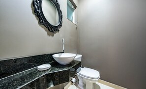 Une salle de bain avec un plan de toilette en marbre noir, un lavabo blanc et des toilettes.
