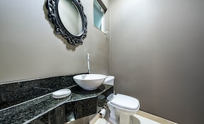 Ein Badezimmer mit schwarzem Marmorwaschtisch, einem weißen Waschbecken und einer Toilette.