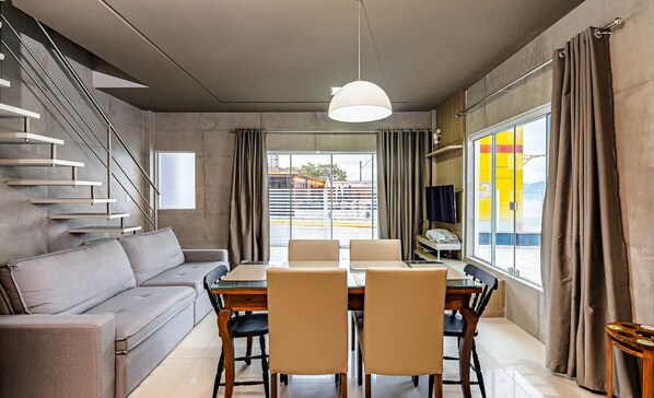 Uma sala de estar moderna com sofá, mesa de jantar, cadeiras e escada.