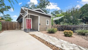 A single-story house with a front porch, a red door, and a stone pathway leading to the entrance.