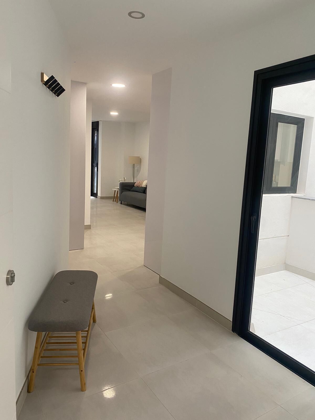 A modern interior with a bench, a sofa, and a large window.
