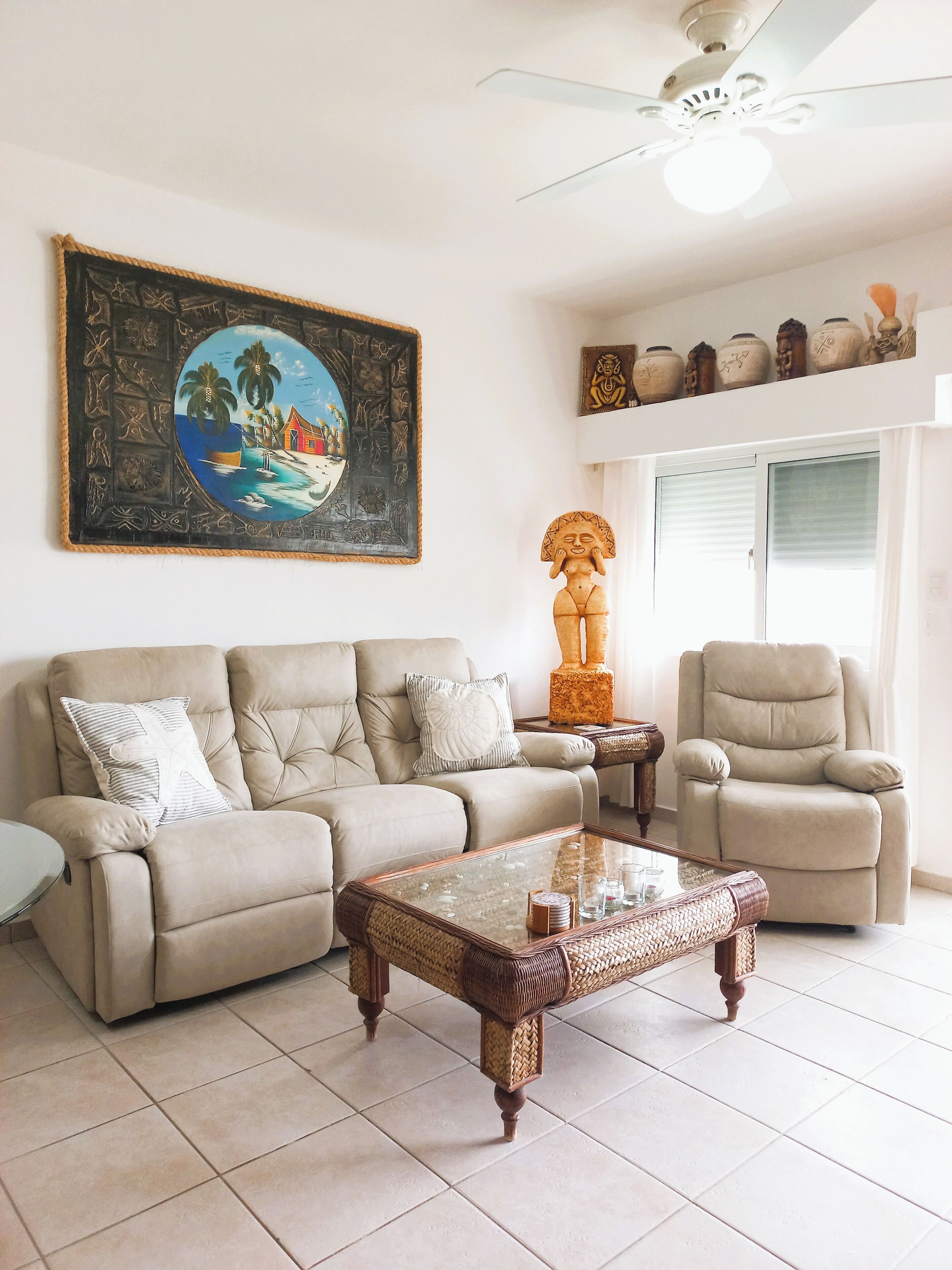 Una sala de estar con un sofá color beige, una mesa de centro de madera y un cuadro en la pared.