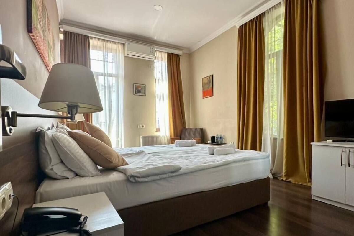 A hotel room with a large bed, bedside table with a lamp, a TV, and a telephone.