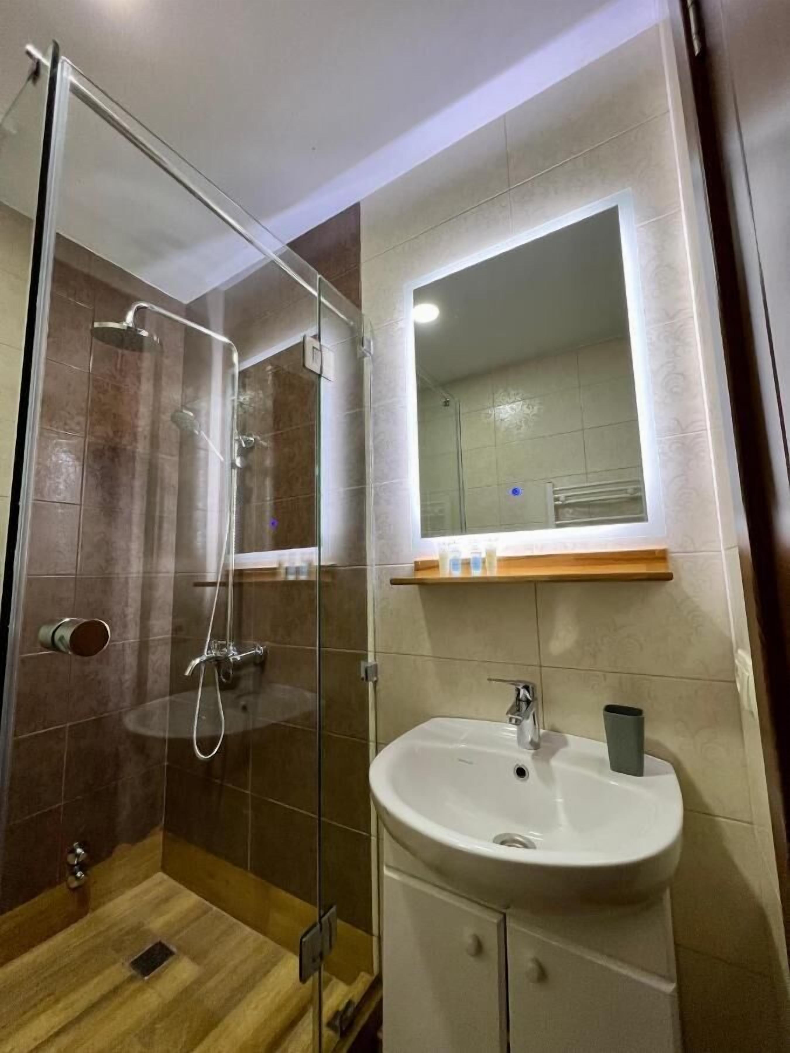 A modern bathroom with a glass-enclosed shower, a white sink, and a mirror above it.