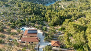 A villa with a swimming pool, solar panels, and a view of the sea.