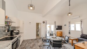 A modern kitchen with a built-in oven, a coffee machine, and a dining area with a table and chairs.