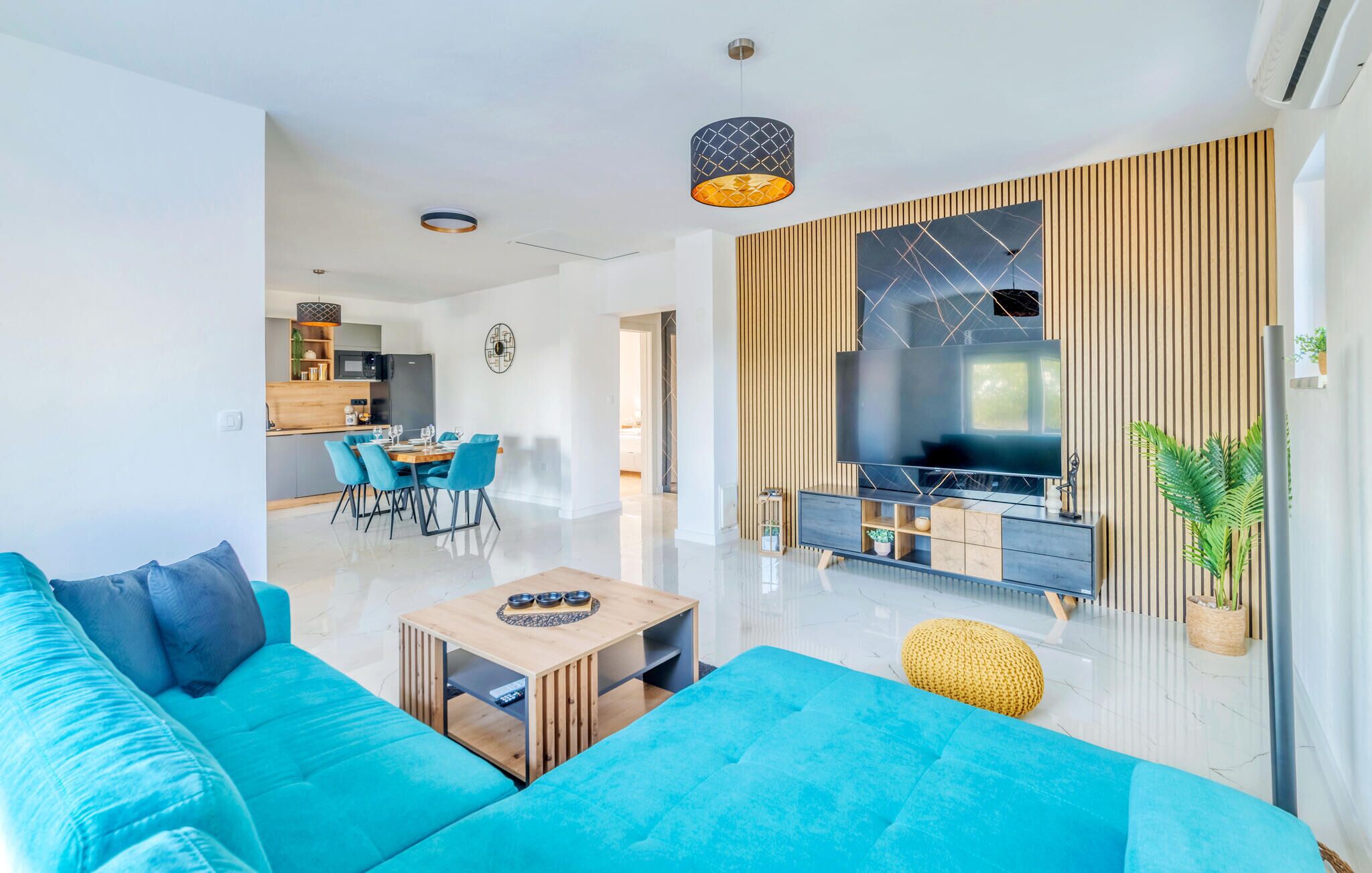 Een moderne woonkamer met een blauwe bank, een houten salontafel en een televisie tegen een houten wand.