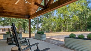 Una terrazza esterna con panche di legno e fioriere in metallo, circondata da alberi e un edificio sullo sfondo.