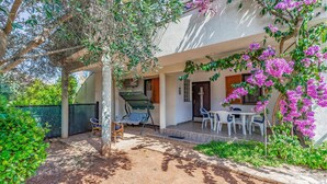 An outdoor patio area with a dining table and chairs, surrounded by greenery and flowering plants. - 1 bedroom amazing apartment in Medulin (Medulin)