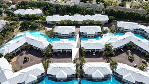 Un resort con varias edificaciones, una piscina central y abundante vegetación circundante.