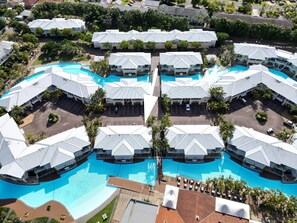 Un resort con varias edificaciones, una piscina central y abundante vegetación circundante.