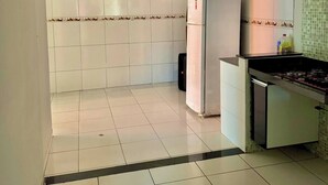 A kitchen with white tiles, a refrigerator, a stove, and a tiled backsplash. - House with Pool and Barbecue (Santa Mônica Guarapari)
