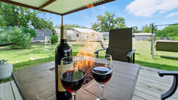 Une terrasse avec une table, deux verres à vin et une bouteille de vin.