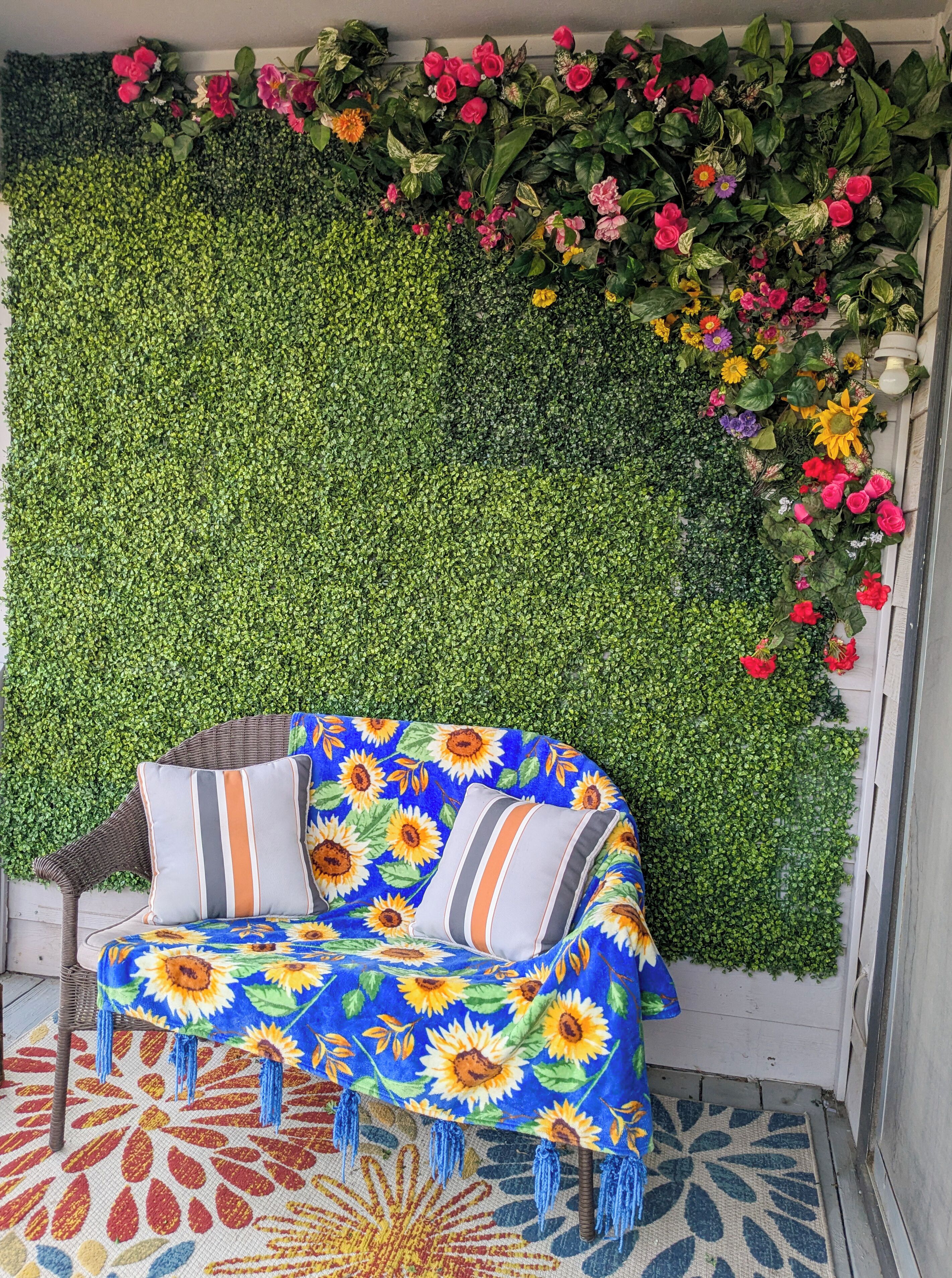 En mysig sittgrupp med en soffa dekorerad med ett solrosmönster, en grön vägg med olika sorters blommor och en mönstrad matta.