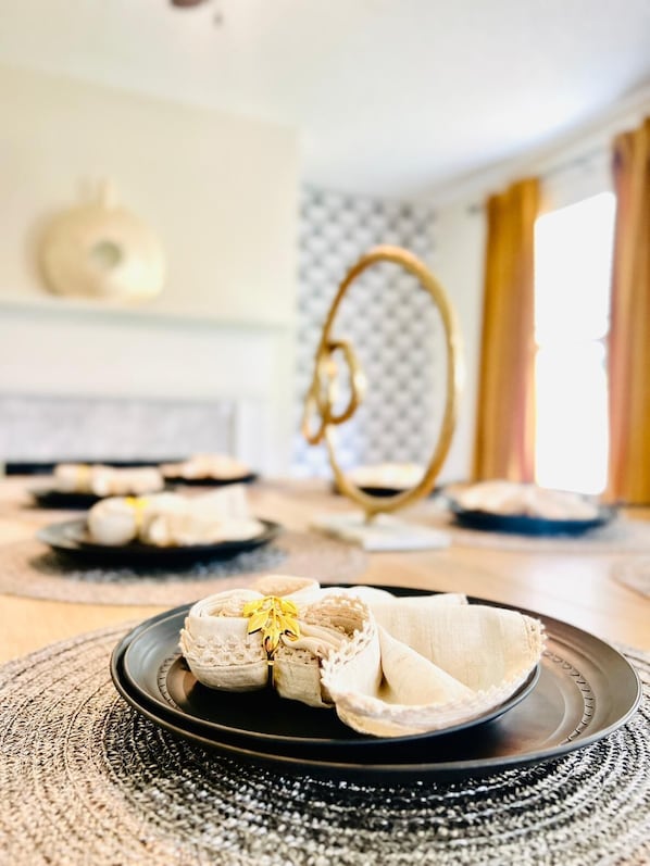 A dining table with plates of food, a hanging light fixture, and a textured wall in the background.
