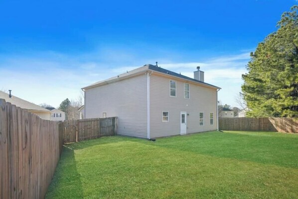 A single-story house with a front yard and a wooden fence.