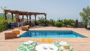 Una piscina con una pérgola y zona de estar al aire libre.