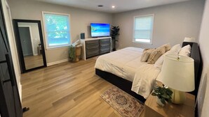 Una camera da letto con un letto, una TV, una cassettiera e una finestra.