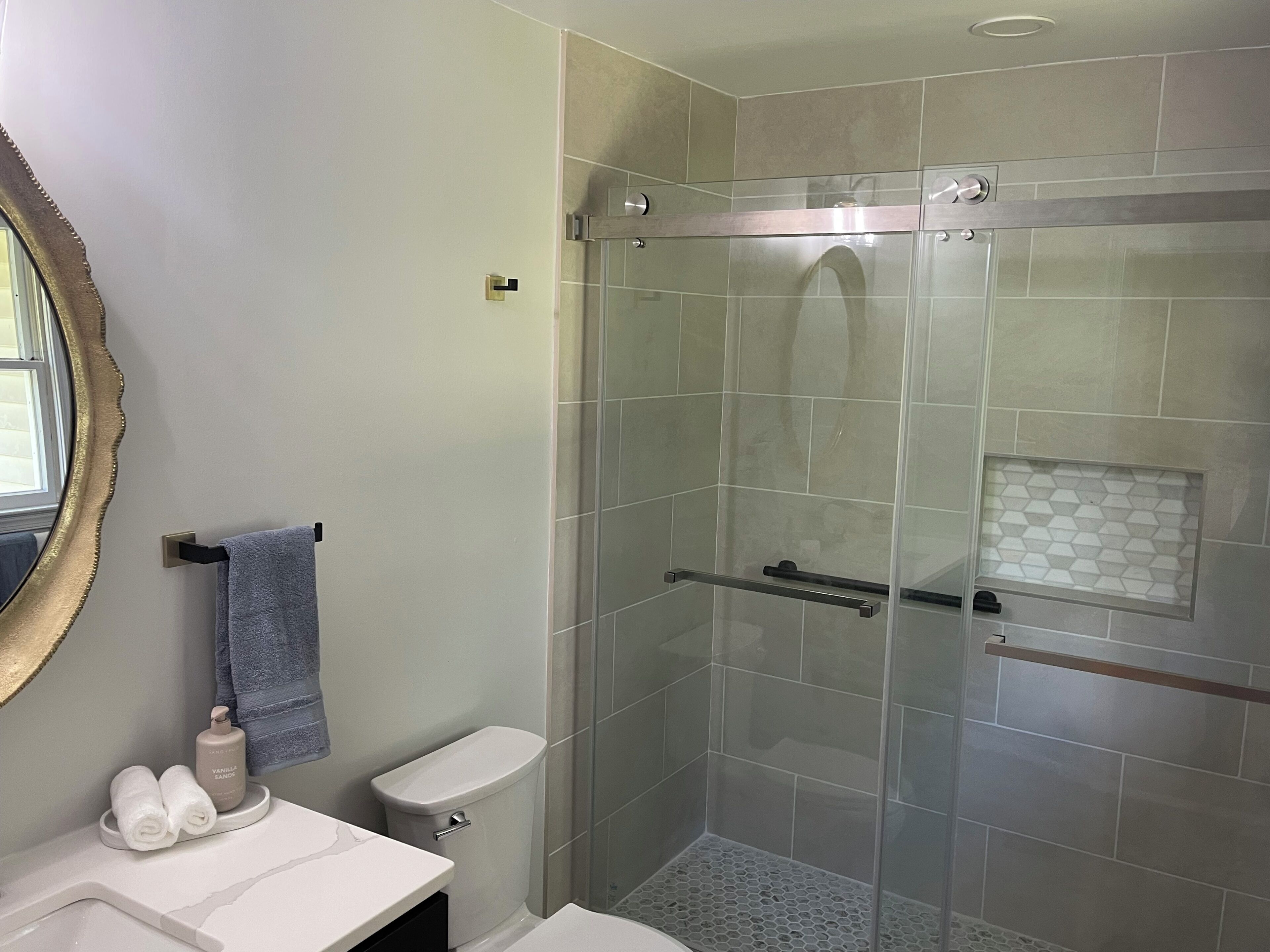 A modern bathroom with a glass-enclosed shower, a toilet, and a vanity with a mirror.
