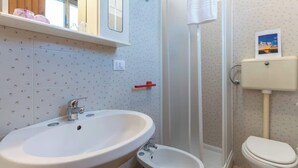 Un bagno con un lavandino grande, un lavabo più piccolo, un water e un box doccia.