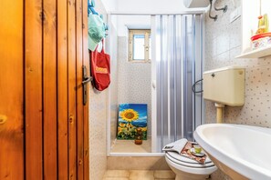 Een badkamer met een houten deur, een douchegordijn, een toilet en een wastafel.