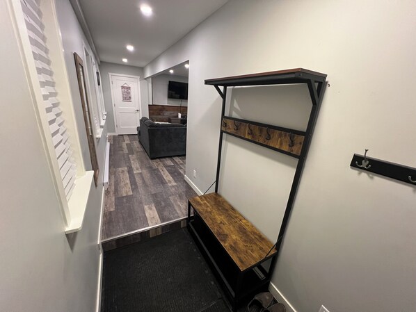 A hallway with a bench, a coat rack, and a door with a sign.