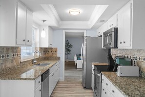 A modern kitchen with granite countertops, stainless steel appliances, and white cabinetry.