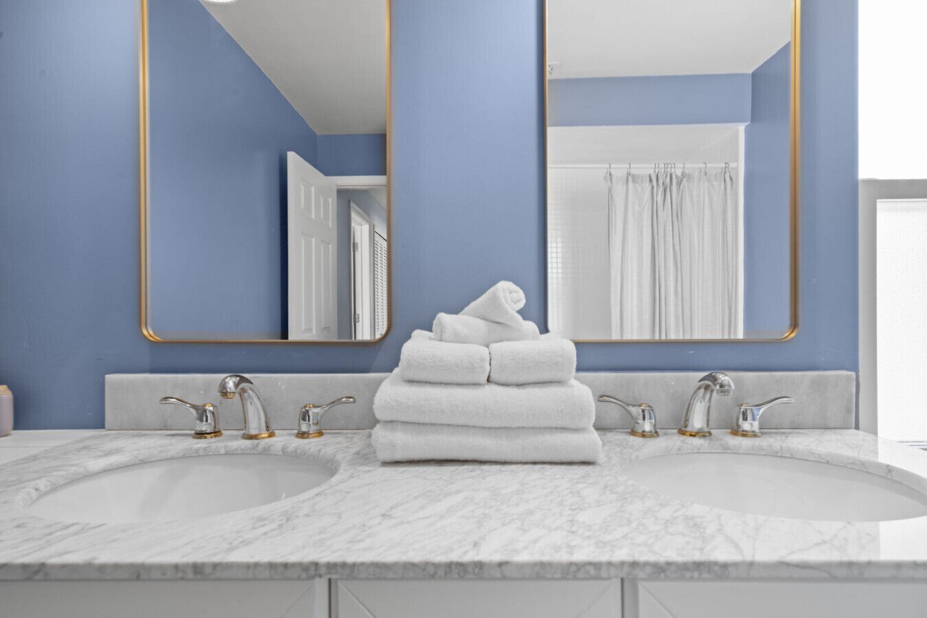 A bathroom with two sinks, a mirror, and a towel stack.