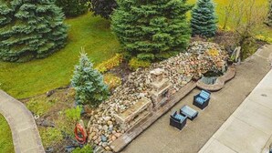 Vista aérea de un jardín ajardinado con un sendero de piedra, un pequeño elemento acuático y mobiliario exterior.