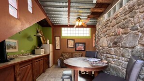 Una cocina rústica con pared de piedra, armarios de madera y una mesa redonda con sillas.