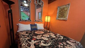Una habitación con una cama, dos espejos en la pared, una lámpara de pie y un cuadro enmarcado.