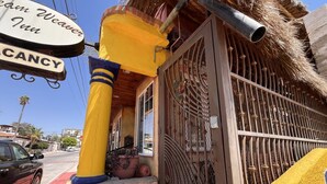 Un bâtiment avec un pilier jaune, une enseigne indiquant « Canny Weaver Inn », et un portail en métal.