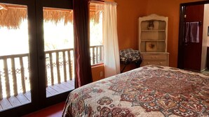 A bedroom with a large bed, a nightstand, a dresser, and a window with curtains.