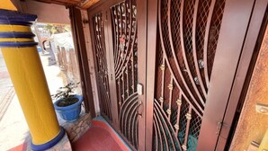 A metal gate with intricate designs, a potted plant, and a wooden pillar.
