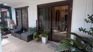 A covered patio with a seating area, potted plants, and a sliding glass door leading to an interior space. - Oasis by Franklin villa #3 (Provincia de Alajuela)