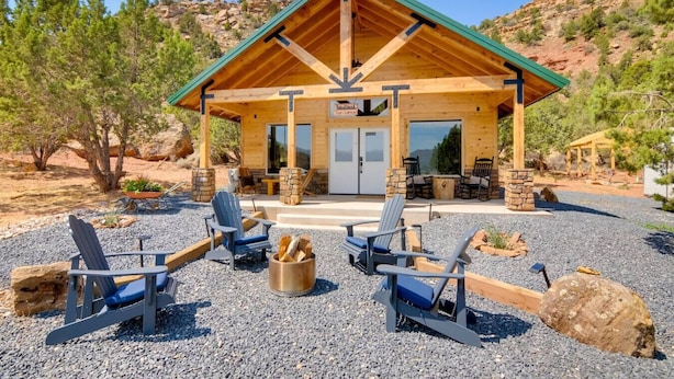 A lodge with a covered patio, outdoor seating, and a view of the surrounding landscape.