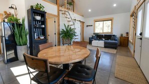 A modern interior with a dining area, a staircase, a sofa, and a large window.