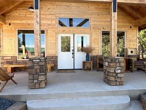 Una baita di legno con camino in pietra, una panca e una porta.