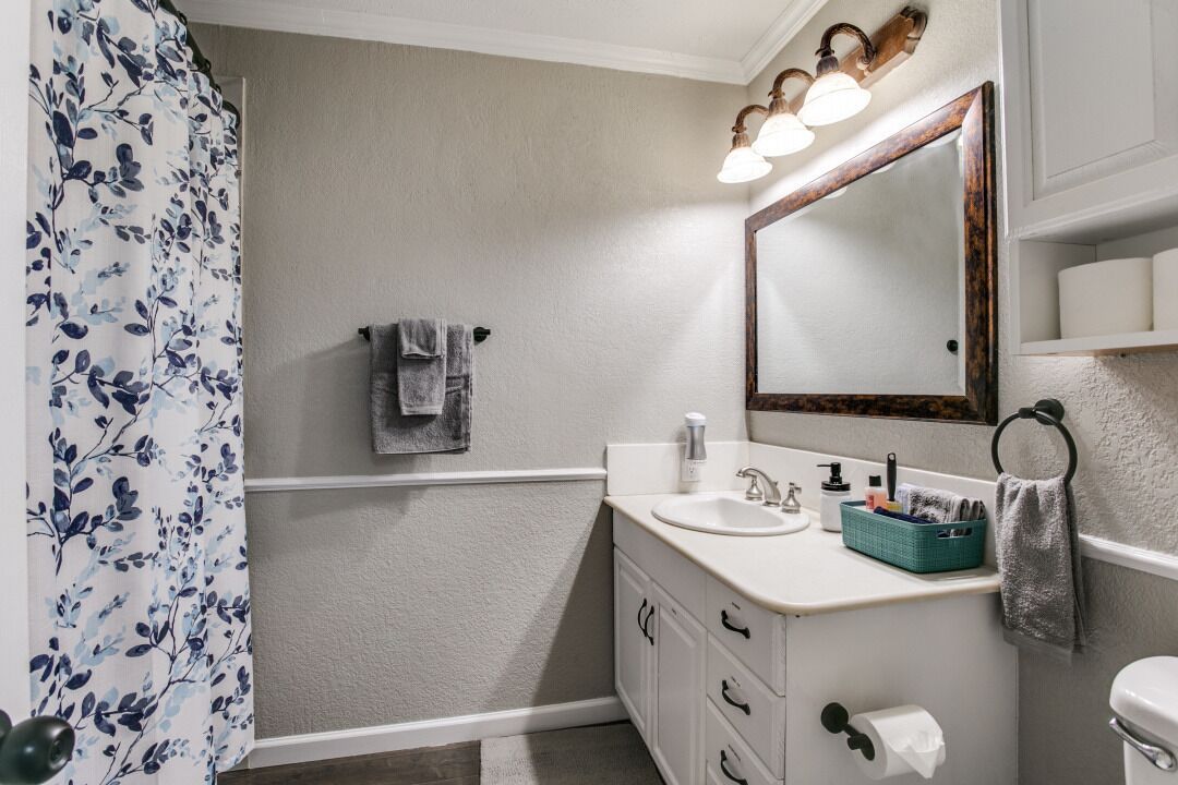 A bathroom with a white sink, a mirror, and a shower curtain with a floral pattern.