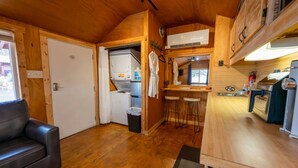 A compact kitchen with a washing machine, a sink, and a bar stool.