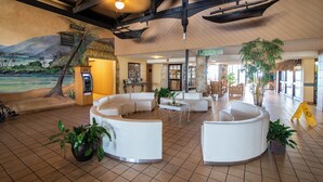 A spacious lobby with a tropical mural, white sofas, and a reception desk. -  Studio for 2 with Breathtaking View with A/C (Daytona Beach Shores)