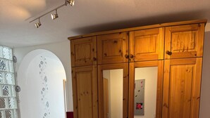 A wooden wardrobe with multiple drawers and doors, a tiled floor, and a glass door with a decorative pattern. - Spacious 130 m² Apartment ,3 Bedrooms, Garden & Parking  ,Sleeps 7 (Riegelsberg)