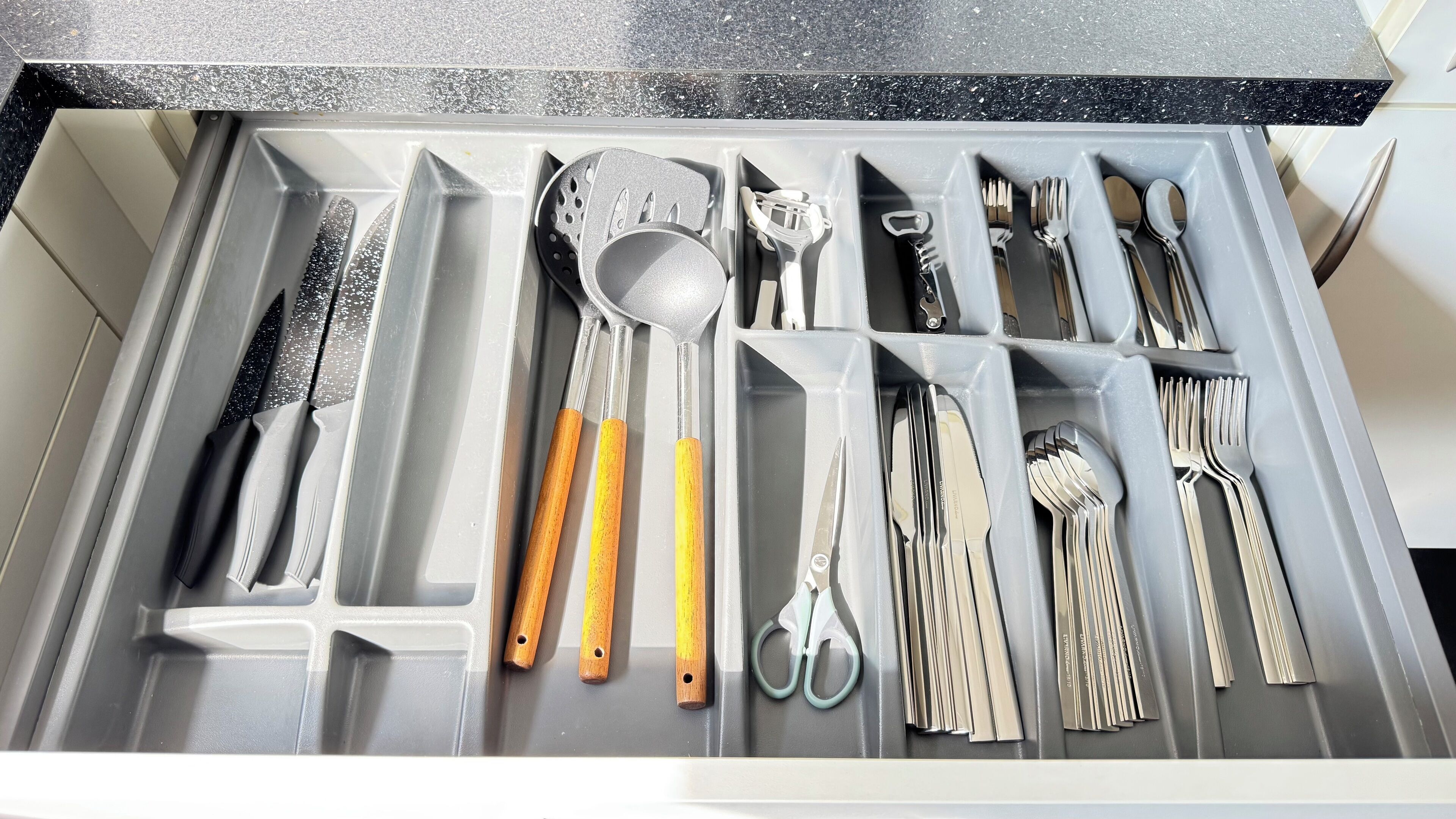 A drawer with various kitchen utensils neatly organized.