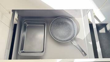 Un cajón de cocina con una bandeja metálica y una sartén antiadherente.