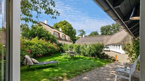 A garden with a lawn, a table with chairs, a bench, and a white car parked in the background. - Amazing home in Aabenraa with WiFi (Aabenraa)