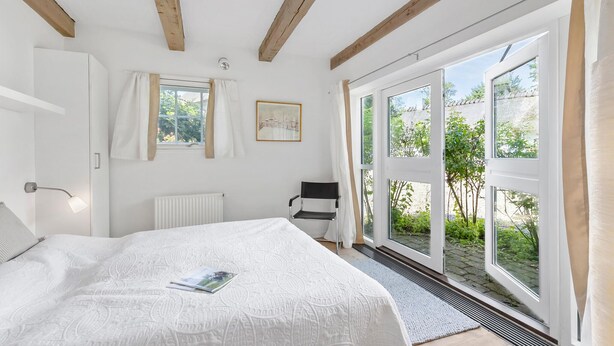 A bedroom with a bed, a radiator, a window with curtains, a chair, and a door. - Amazing home in Aabenraa with WiFi (Aabenraa)